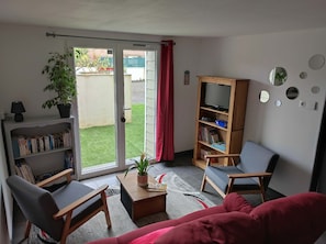 Una sala de estar con un sofá, sillas, una mesa de centro, una estantería y un televisor.