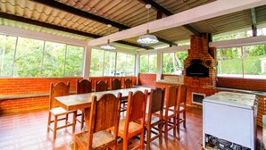 A restaurant with a brick fireplace, wooden tables and chairs, large windows, and a tiled ceiling. - Country house with heated pool, 7 bedrooms with air conditioning near São Paulo. (Juquitiba)