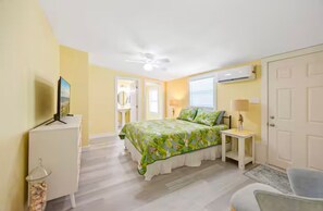 A bedroom with a bed, a ceiling fan, a TV, a desk, and a chair. - Cocoa Beach Getaway just a block from the beach! (Cocoa Beach)