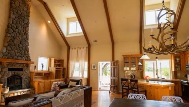 A spacious living area with a stone fireplace, wooden furniture, and a chandelier. - Capay Valley Country Home (Guinda)
