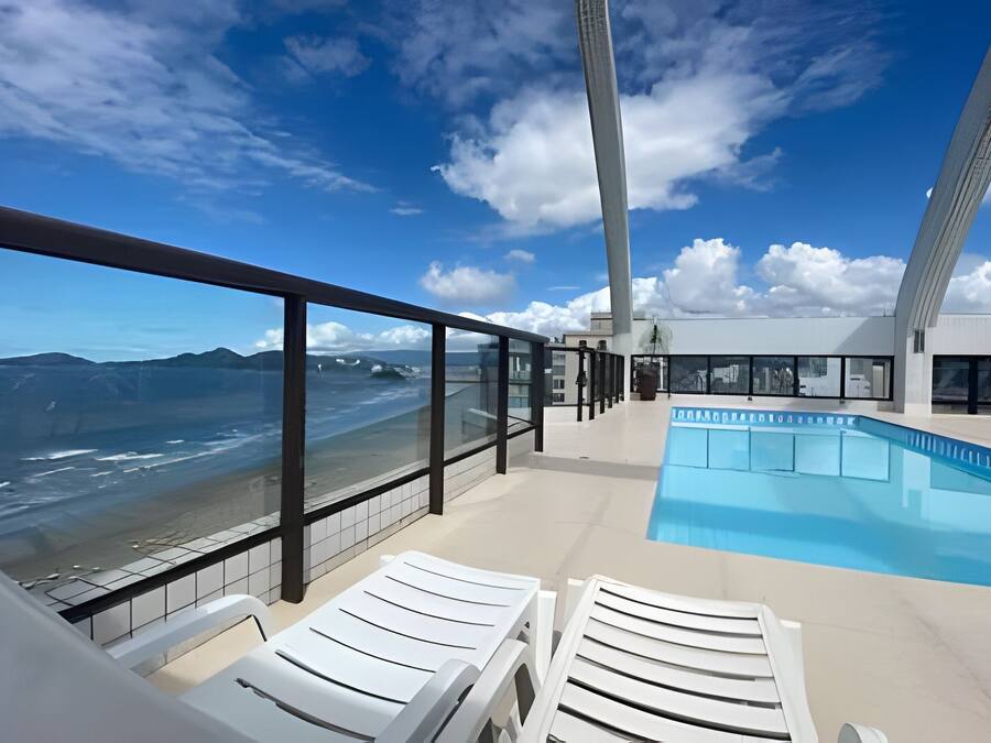 A pool area with a view of the ocean and mountains.