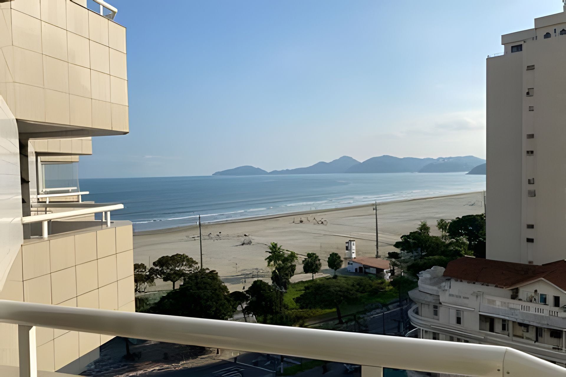 Blick auf die Küste vom Balkon mit Strand und Bergen im Hintergrund.