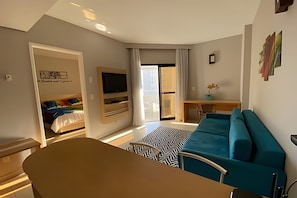 Een moderne woonkamer met een bank, een televisie en een eethoek.