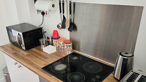 A modern kitchen with a black stove, a toaster, and a coffee maker. - Cosy Flat in Hammersmith - Close to tube station / But very quiet location (London)