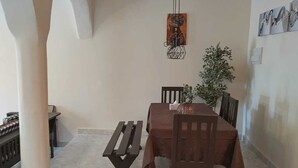 Un espace repas comprenant une table, des chaises, un banc, un luminaire suspendu et un tableau accroché au mur.