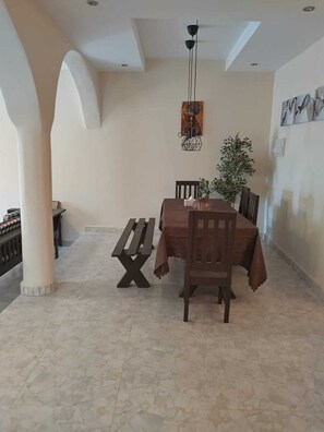 Ein Essbereich mit Tisch, Stühlen, einer Bank, einer Hängelampe und einem Wandbild.