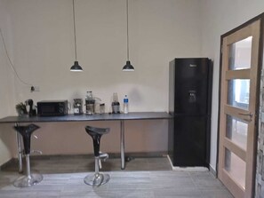 Eine Küche mit Kühlschrank, Mikrowelle, Kaffeemaschine und zwei Barhocker.