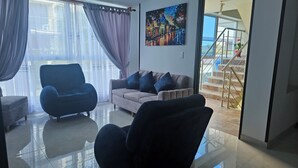Un salon avec un canapé, un fauteuil et un tableau accroché au mur.