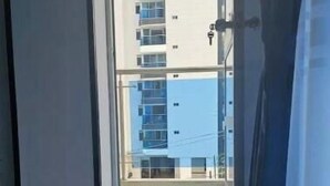 Un couloir menant à un balcon d’où l’on peut admirer un immeuble de grande hauteur.