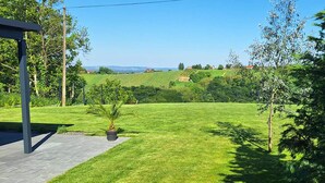 A well-maintained lawn with a small palm tree, a paved walkway, and a clear view of distant hills.