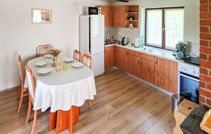A kitchen with wooden cabinets, a white refrigerator, and a dining table set for four.