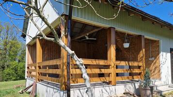 A building with a wooden porch, a hanging bucket, and a potted plant.