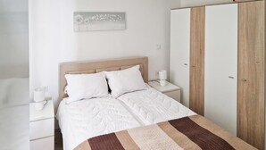 Ein Schlafzimmer mit einem Bett, Nachttischen, einem Kleiderschrank und einem an der Wand hängenden Kunstwerk.