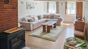Ein Wohnzimmer mit einer Sofagarnitur, einem Couchtisch, einem Kamin und einem Kreuz an der Wand.
