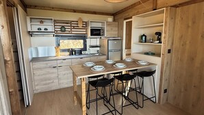 Une cuisine compacte avec des meubles en bois, un îlot central doté de tabourets et un luminaire suspendu.
