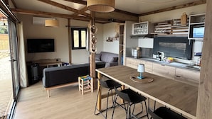 Une cuisine moderne avec des poutres en bois, un coin repas avec des tabourets, un canapé et un téléviseur.