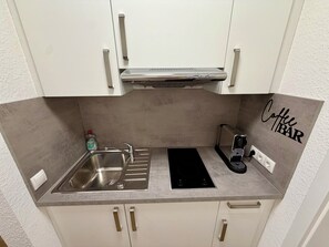 Eine kleine Küche mit Spüle, Kaffeemaschine und einem an der Wand befestigten Schild mit der Aufschrift 'Coffee Bar'.