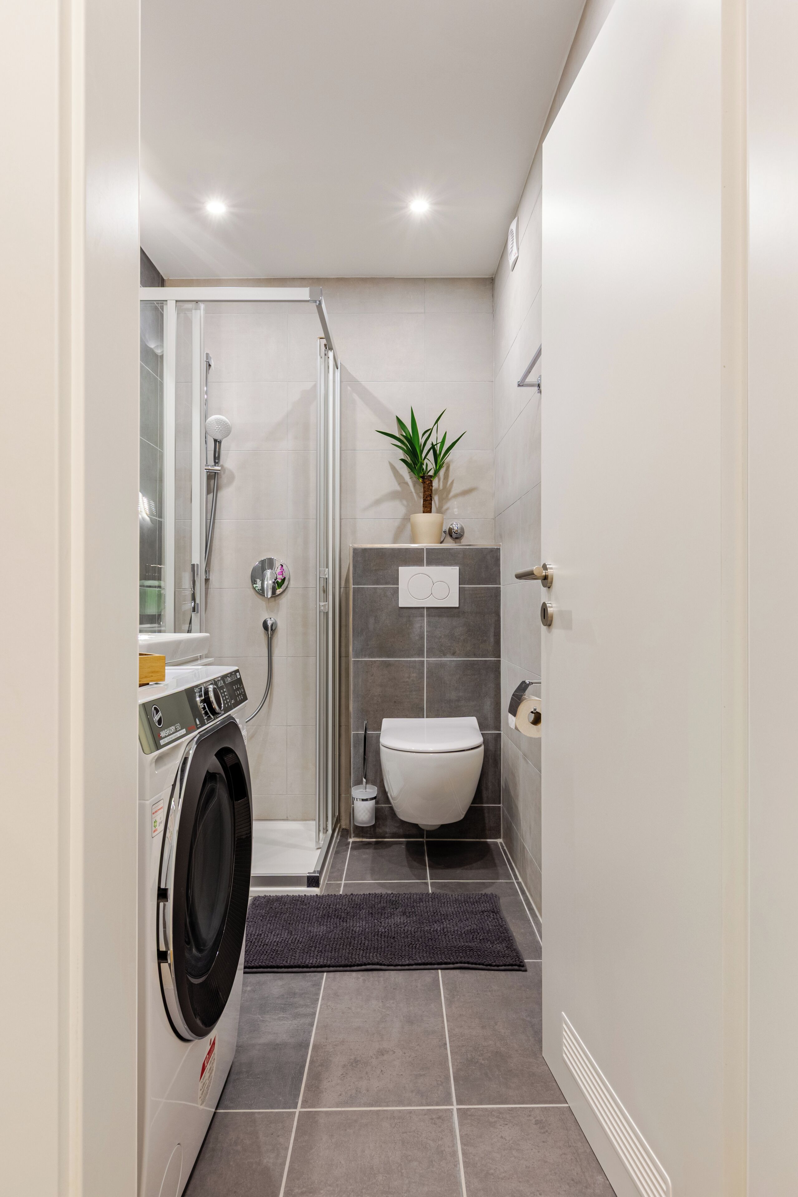 Ein kleines Badezimmer mit Duschkabine, Toilette und Waschmaschine.