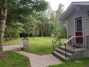 A house with a front porch, a small shed, and a grassy yard with trees. - Secluded Forest Haven | Hot Tub | 5 Min to Beach (Innisfil)