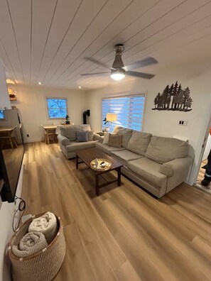 A living room with a sofa, a coffee table, and a ceiling fan. - Secluded Forest Haven | Hot Tub | 5 Min to Beach (Innisfil)