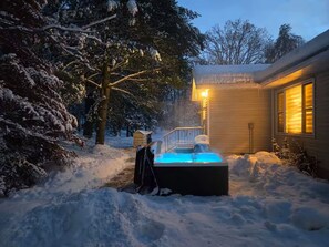 A snow-covered outdoor area with a hot tub and a wooden building with a lit window. - Secluded Forest Haven | Hot Tub | 5 Min to Beach (Innisfil)