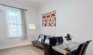 Una sala de estar moderna con un sofá, una mesa de centro de vidrio, una lámpara y un adorno en la pared.