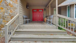 A stone wall, a red door, and a porch with two benches.