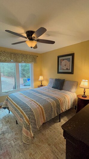 A bedroom with a bed, two bedside lamps, a ceiling fan, a window with curtains, and a framed picture on the wall. - Spacious Lakefront Apt w/ Deck in Fayetteville! (Fayetteville)
