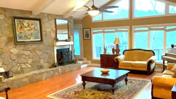 A spacious loft with a high ceiling, stone wall, large windows, and a fireplace.