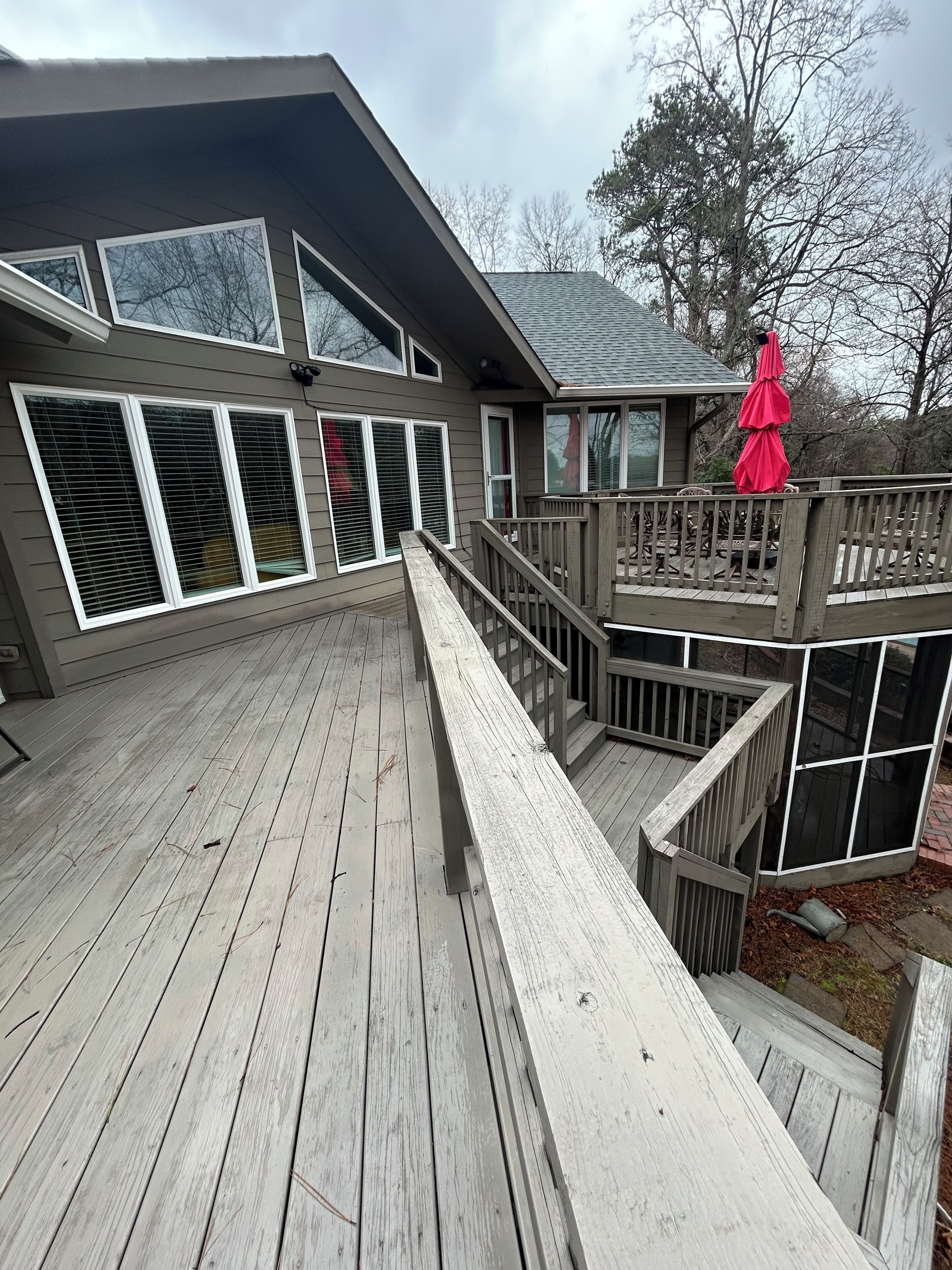 A multi-level deck with wooden railings and a red umbrella.