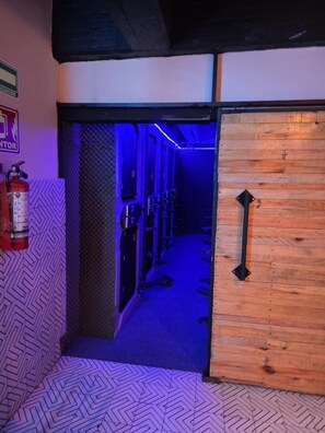 A narrow hallway with a patterned floor, a fire extinguisher on the left, and a wooden door with a black handle on the right. - Hotel Capsula Condesa (Mexico City)