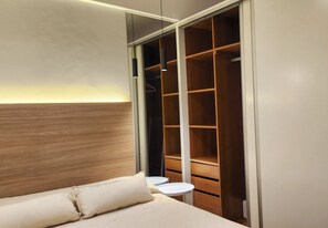 Ein Schlafzimmer mit Bett, Nachttisch, Kleiderschrank und einer Pendelleuchte.