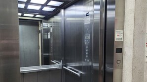 En hiss med metalldörrar, ett handräcke och instruktioner för nödsituationer.