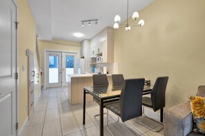 Una cucina moderna con zona pranzo, che include un tavolo e sedie in vetro, un forno a microonde integrato e una lampada a sospensione.