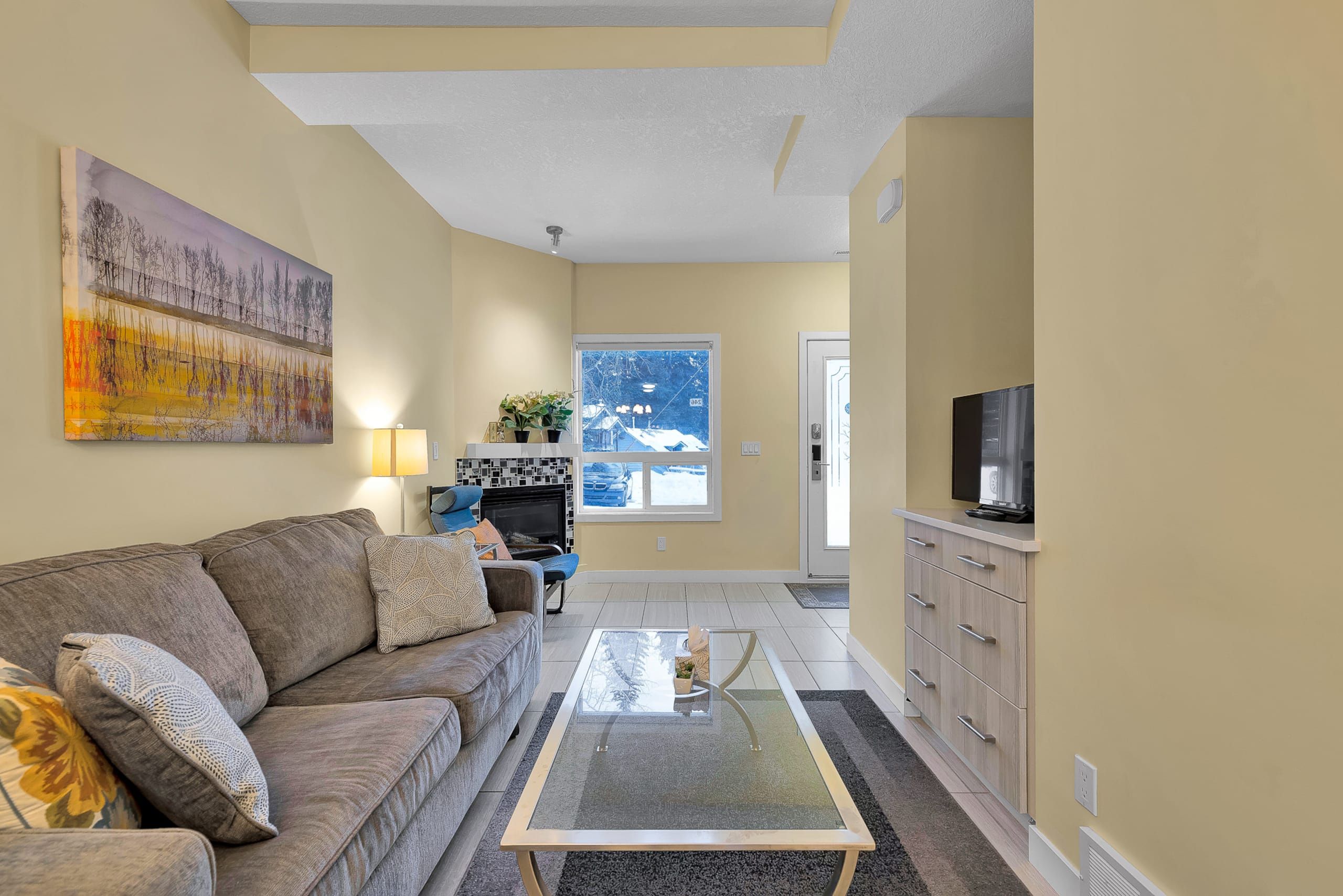 A living room with a sofa, a glass coffee table, a fireplace, and a television.