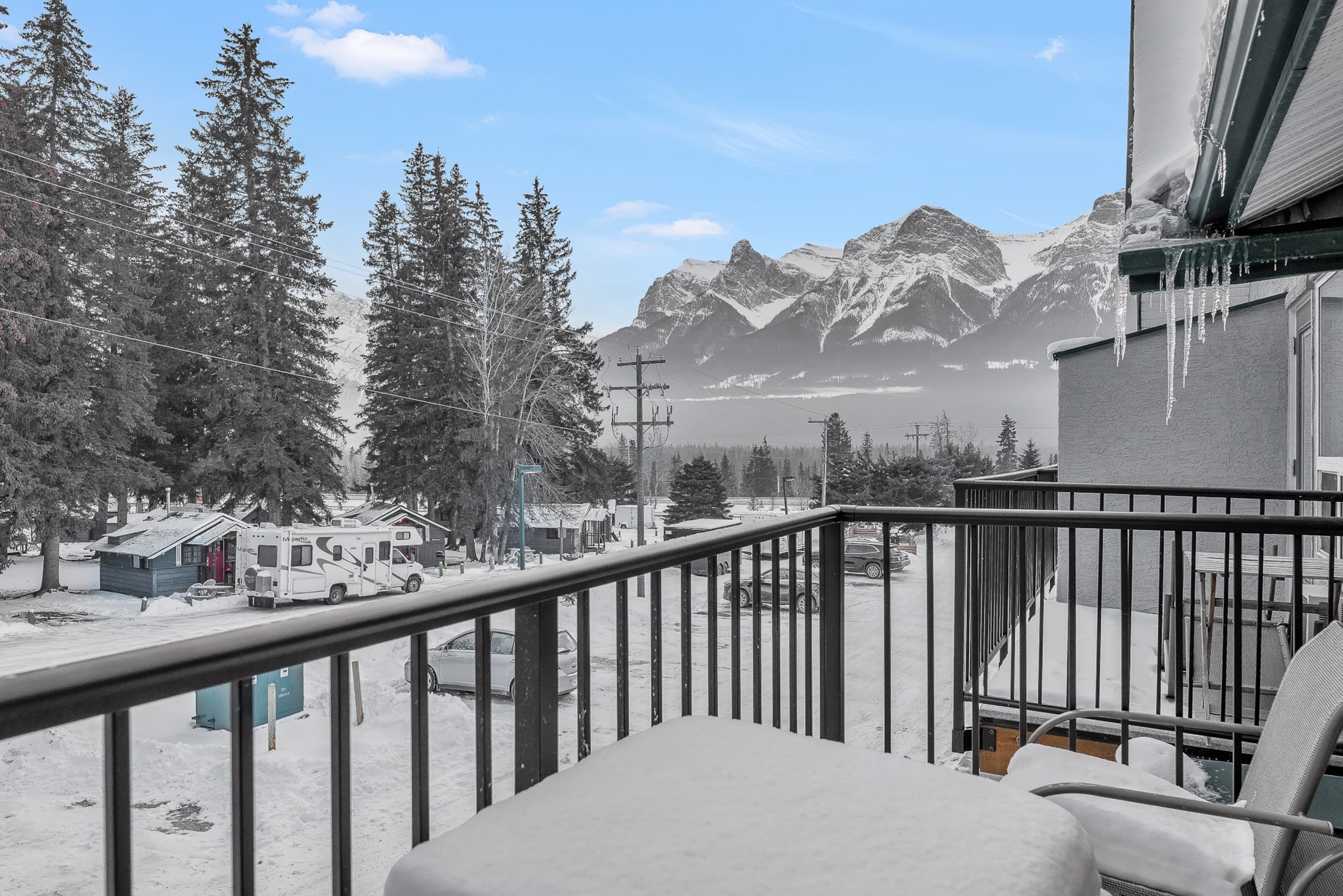 A balcony with a view of snow-covered mountains and trees.
