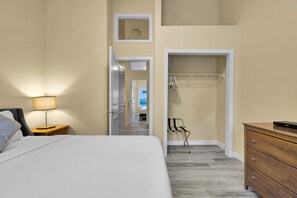 A hotel room with a bed, a nightstand, a lamp, a wooden dresser, and a walk-in closet with hanging clothes. - B246- Townhouse near Banff gate, Free Parking (Harvie Heights)
