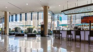 Eine geräumige Lobby mit Barbereich, großen Fenstern und Blick auf hohe Gebäude.