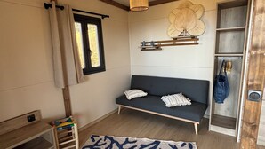 Una habitación con sofá, alfombra estampada, lámpara colgante y techo con vigas de madera.