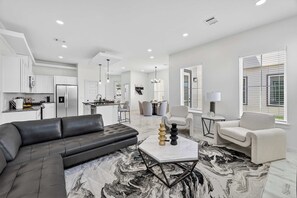 A modern living room with a black leather sofa, a marble-patterned rug, and a white coffee table. - Executive Home, Office, Galleria & NRG (Houston)
