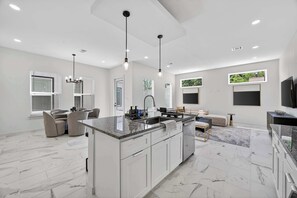 Een moderne keuken met een centraal eiland, witte kastjes en hanglampen.