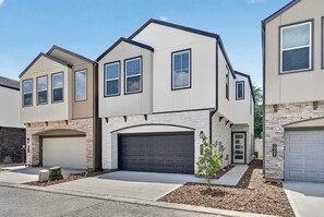 A modern two-story house with a garage, a small front yard, and a stone accent wall. - Upscale Home, Office, Galleria & NRG (Houston)