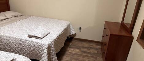 A bedroom with two beds, a wooden dresser, and a mirror.