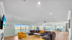 A spacious living area with a large sofa set, yellow bean bag chairs, and a dining table. - Serene 4-bedroom house with AC in Bolivar Peninsula (Bolivar Peninsula)
