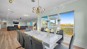 A modern dining area with a marble table, black chairs, and a chandelier. - Serene 4-bedroom house with AC in Bolivar Peninsula (Bolivar Peninsula)