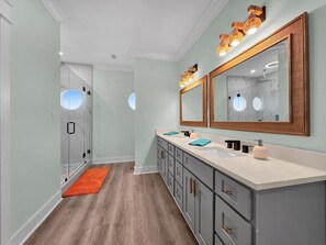 Une salle de bain avec un double vasque, un miroir et un espace douche.