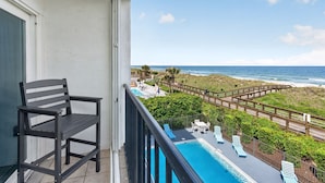 Un balcón con vista al océano, una piscina y una silla.