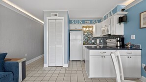 Una cocina moderna con armarios blancos, una pared de acento azul y un letrero que dice 'SUN SAID SEA'.