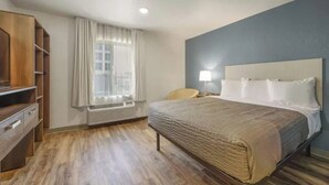 Une chambre d’hôtel avec un lit, un bureau, une chaise et une fenêtre avec des rideaux.