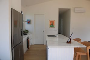 A modern kitchen with a refrigerator, stove, and sink. There is a door leading to another room.